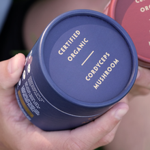 Load image into Gallery viewer, Hand holding a container labeled &#39;Certified Organic Cordyceps Mushroom&#39;

